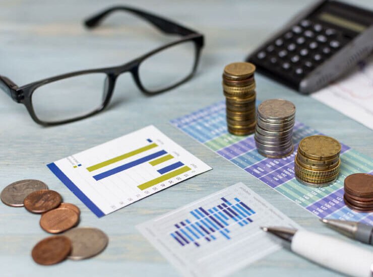 Glasses, coins, calculator, pen and some calculation on the desk, Investieren in Serbien.